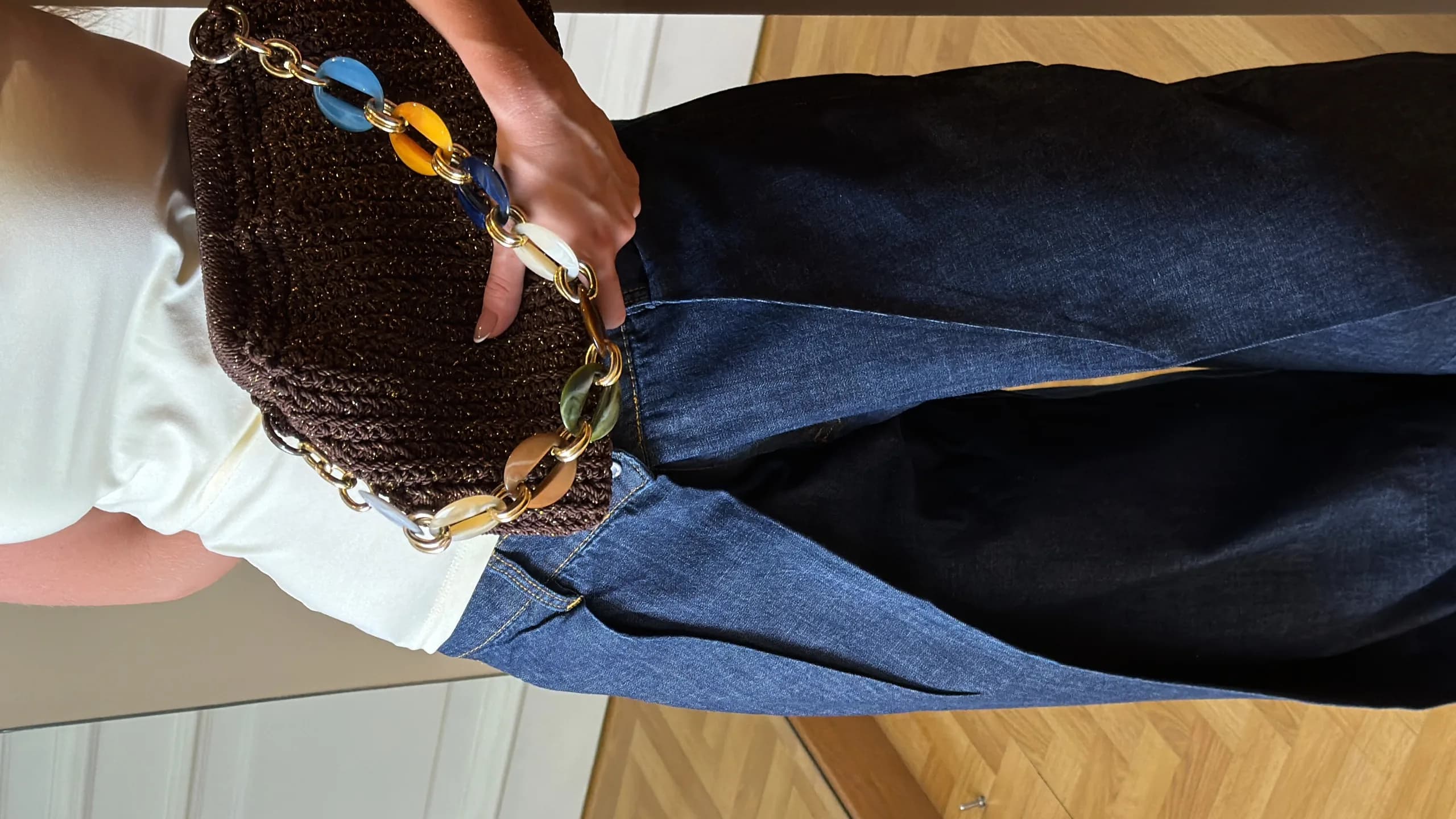 Chain-link bag held against a denim outfit